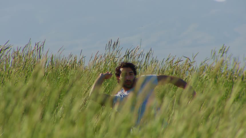 Man dancing moving his arms amidst vegetation on a hill