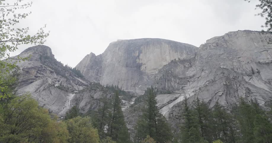 Yosemite valley unfolds beneath the sheer granite face of half dome its snowcapped peak a beacon against the vast california sky