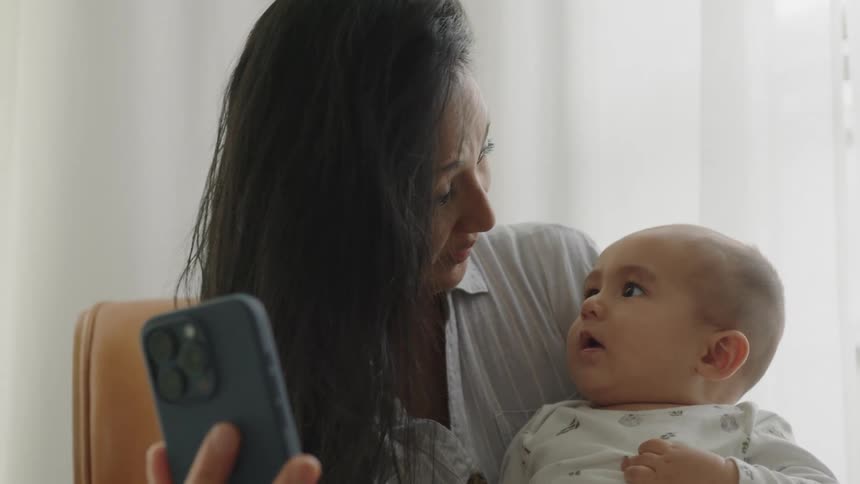 A clip of a mother holding a phone while playing with her kid