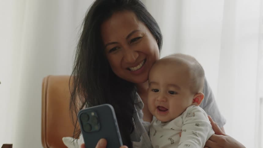 Mother holds a phone in front of her baby