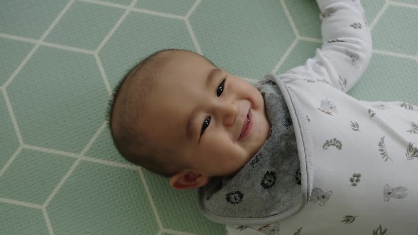 A baby is laughing as he lays down