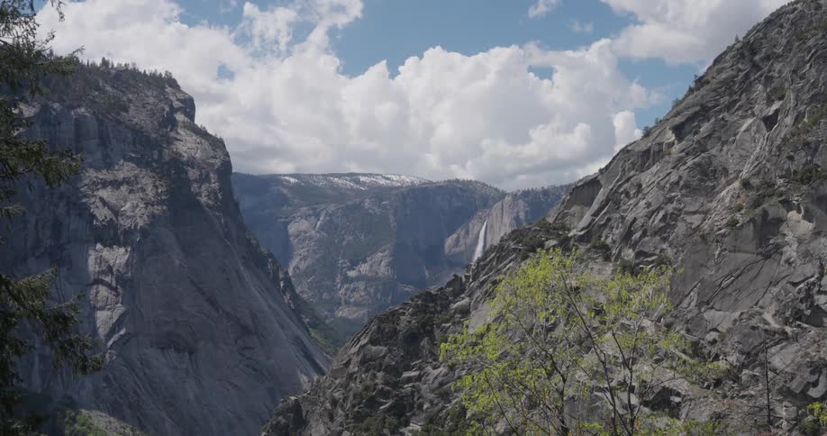 The cascading waterfall tumbles down the rocks into a pool of turquoise water in the valley below the snowcapped mountains