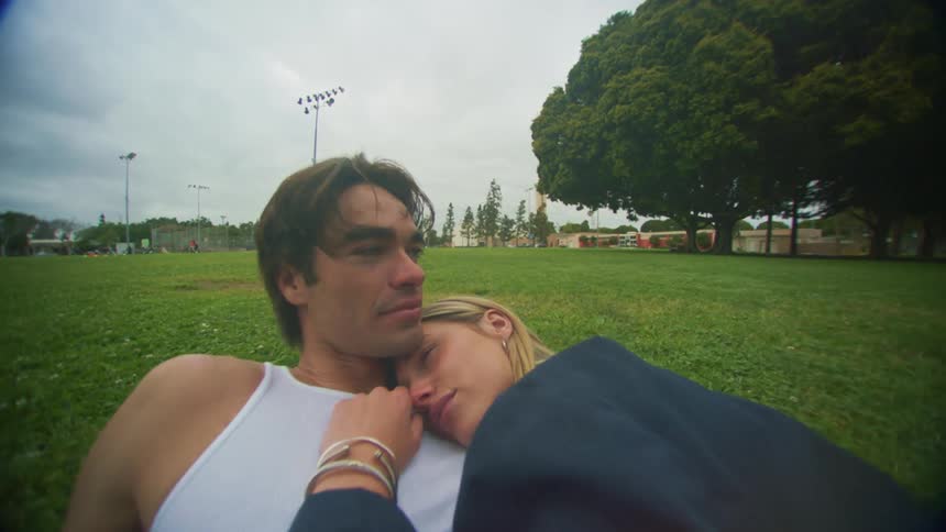 A couple embracing while lying in the grass in a park