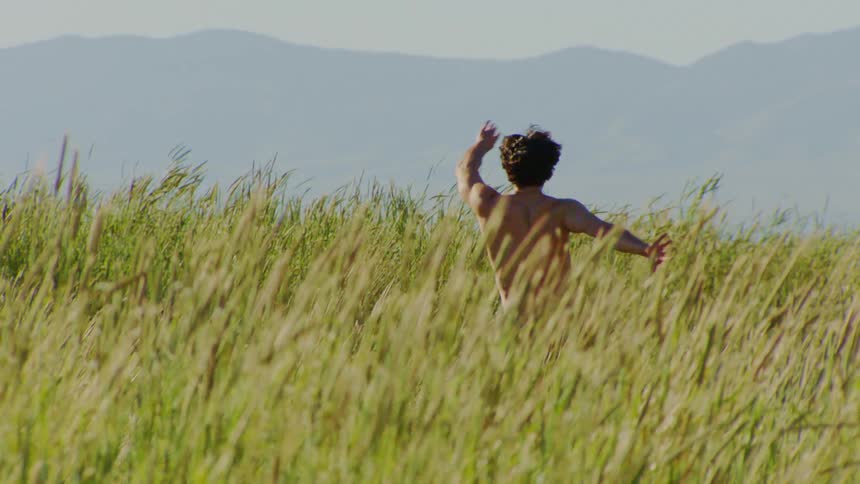 Man without shirt in nature dancing on a clear blue sky day