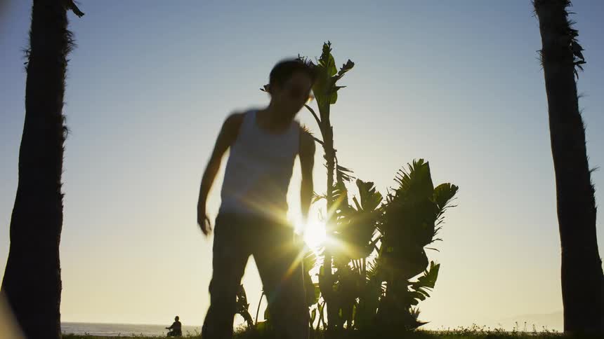 A young asian man dancing outdoors at sunset