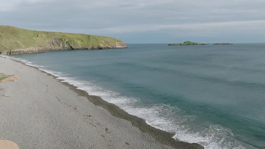 Aerial aerial panorama of the rocky coast with vegetation on the edge of a calm beach