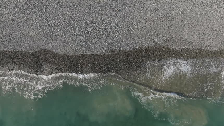 Topdown view of waves gently crashing on the coastline