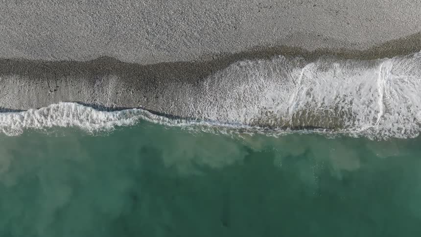 The turquoise water laps gently at the shore of this secluded beach framed by dramatic cliffs