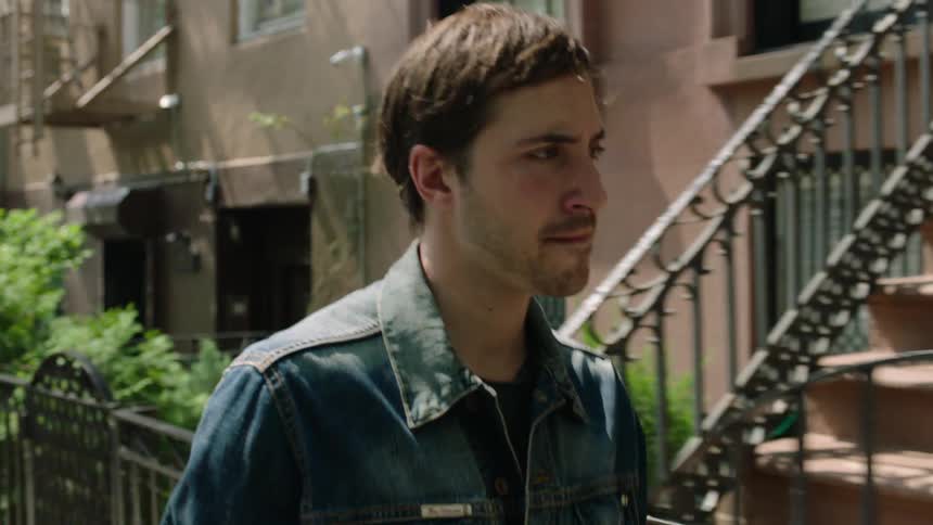 A man walks on a sidewalk in a city