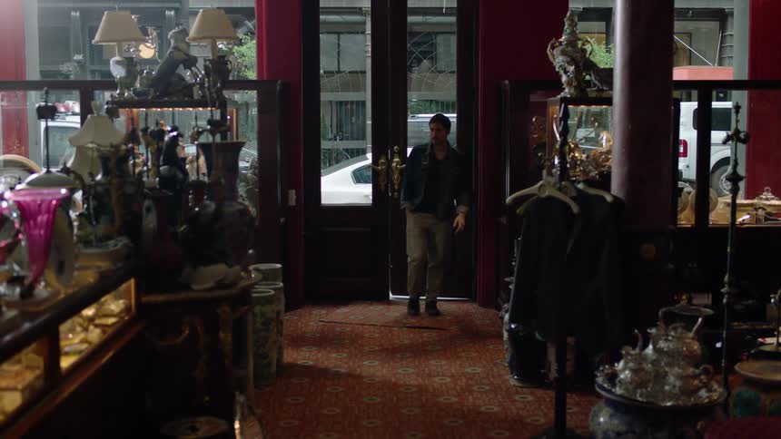 A man enters the door of an antiques store and looks around