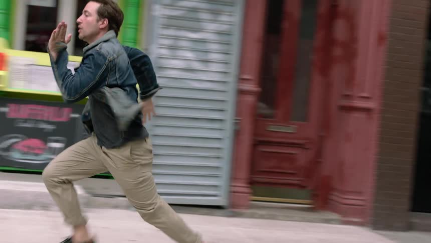 A man runs down a city sidewalk