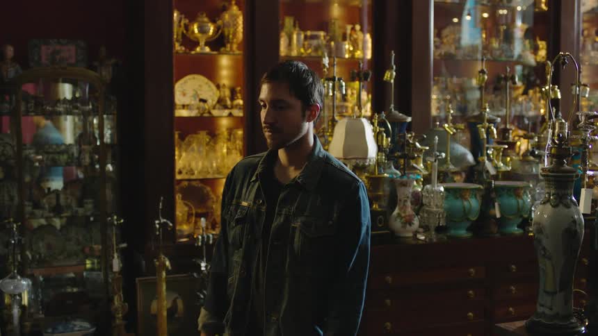 A man walking into a store filled with antiques