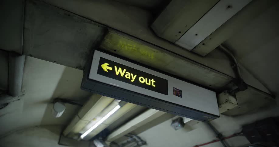A station sign reading way out with an arrow pointing left