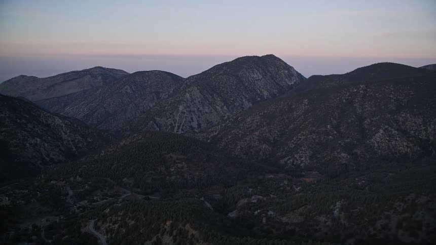 Aerial landscape of mountain ranges with vegetation against a purple morning sky