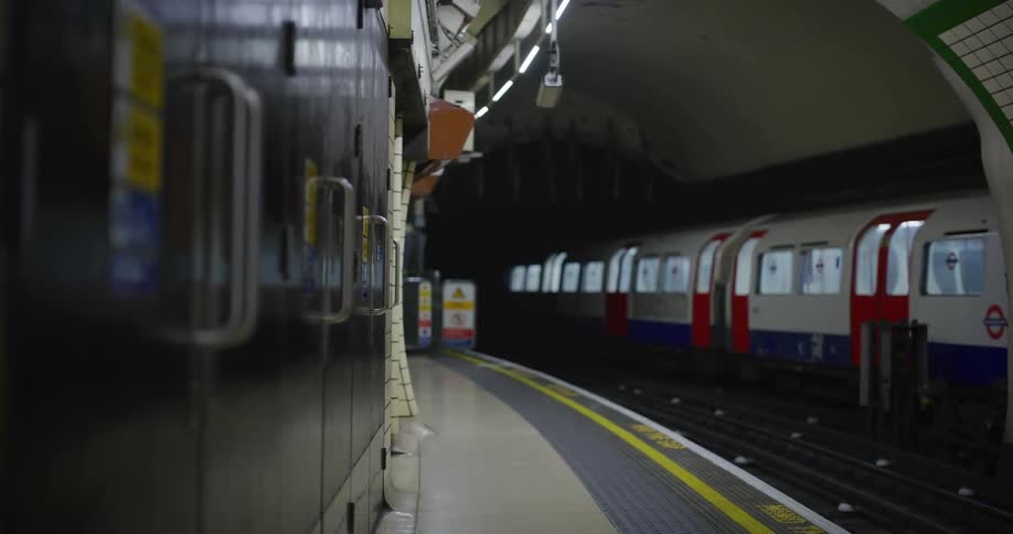 A train enters an underground train station with a curved platform