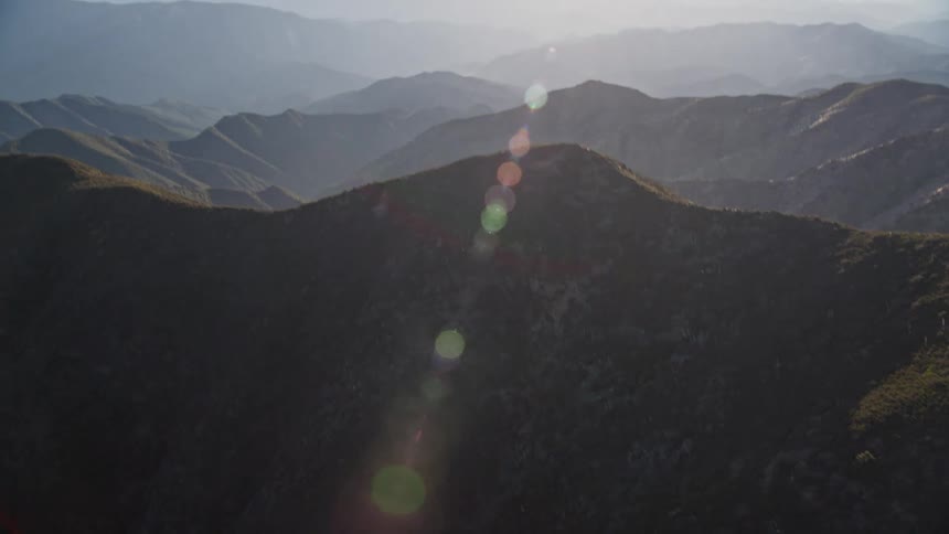 A landscape view of rolling hills under a hazy sky under sunlight