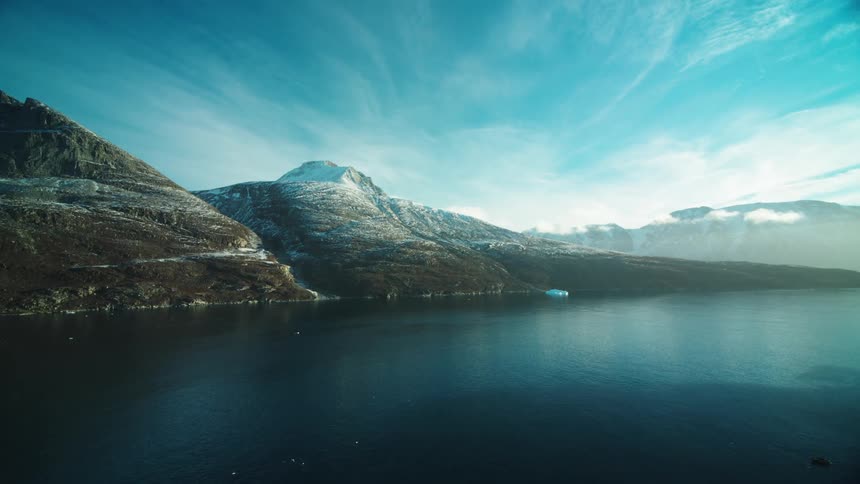 Aerial panorama of a sea at the edge of mountains with snowcapped peaks
