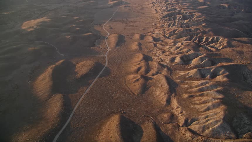 Aerial panorama of a road that winds through a desert environment and next to mountains