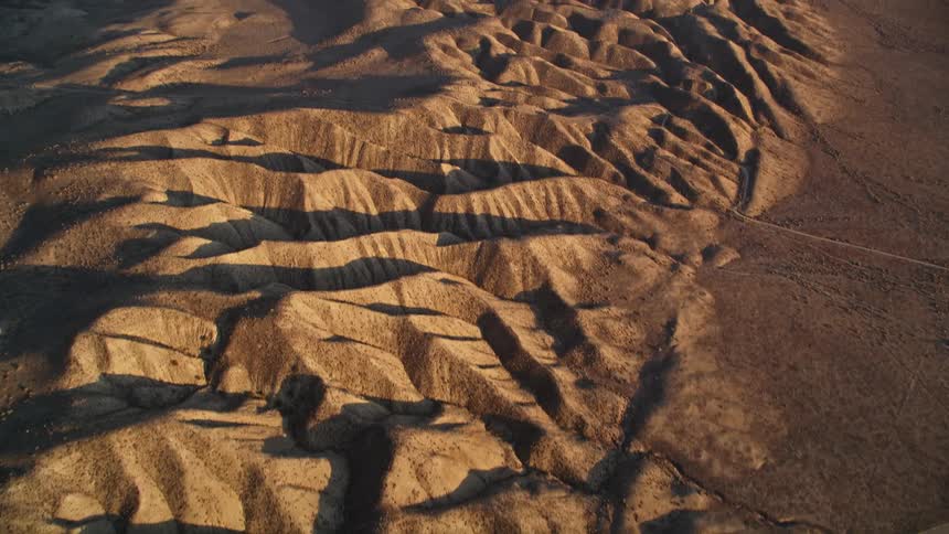 A road crossing desert terrain covered in sandy hills