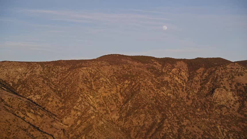 The moon visible over a mountain range