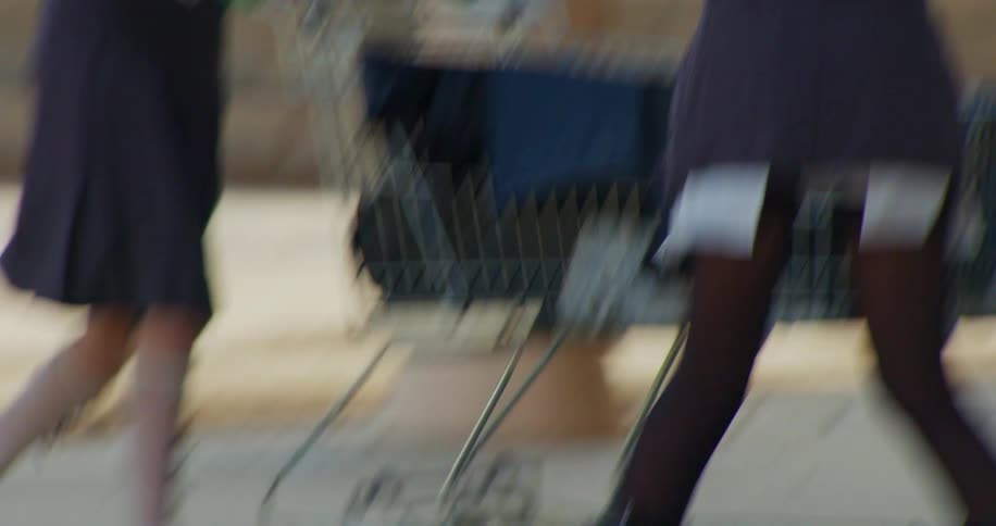 Two people are pushing a shopping cart outside