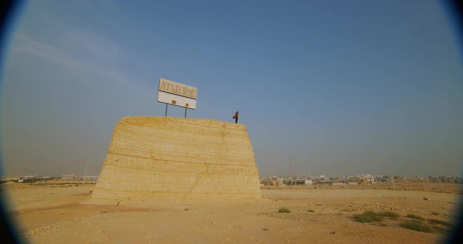 Person on top of a ravine with a sign on an empty lot