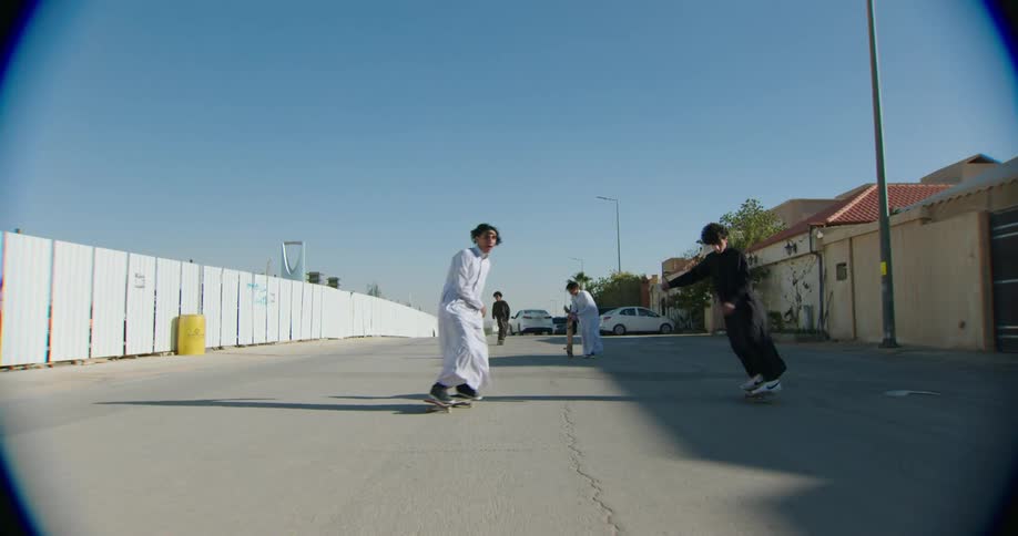 Four teenage boys ride skateboards in a street