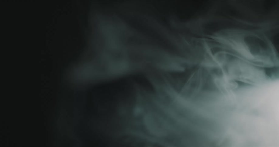Flashing light and dense smoke passing against a dark background