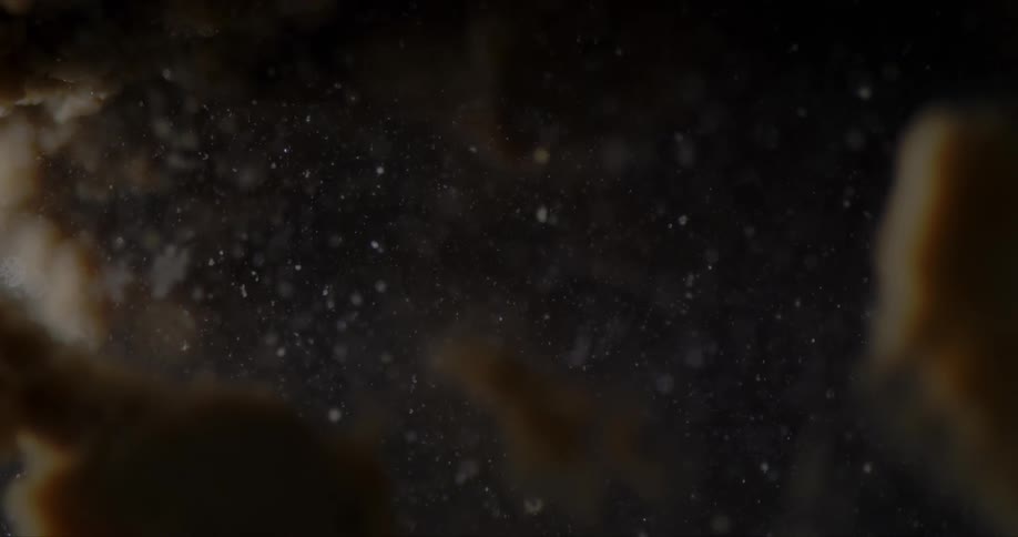 Dust particles floating on a clear liquid with blurry shapes in the foreground