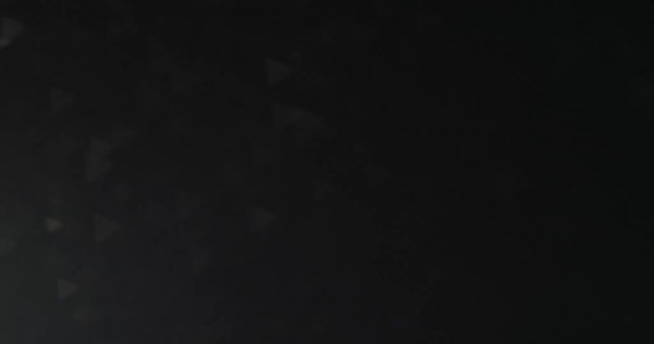 Scattered moving triangular shapes against a dark background