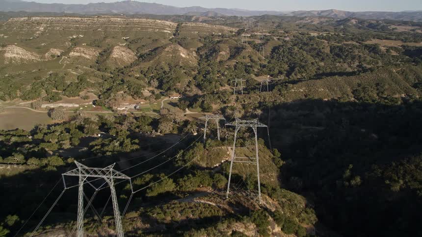 The highvoltage power lines snake across the rugged mountain terrain