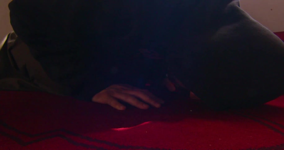 A person kneeling over a red carpet to pray