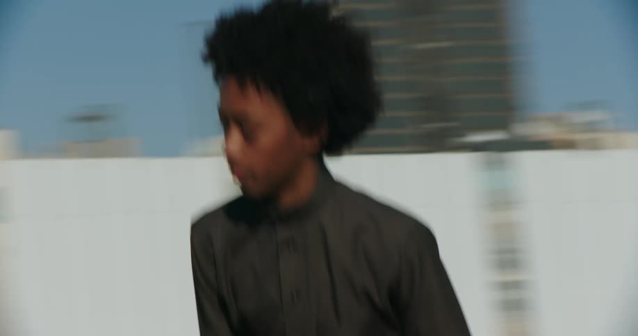 A group of teenagers wearing thobe skateboards down the street
