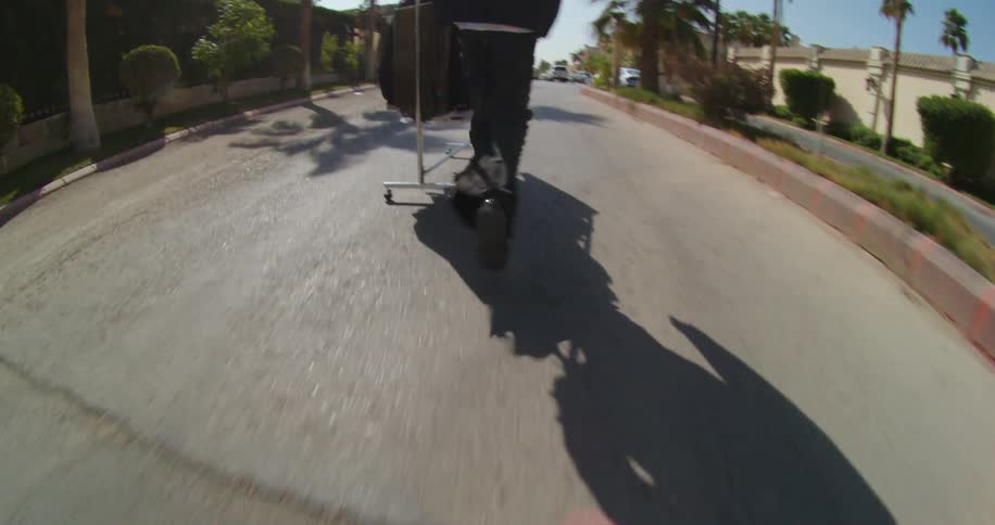 Man walking on the street of a metropolis carrying a cart with hangers of fashion clothes