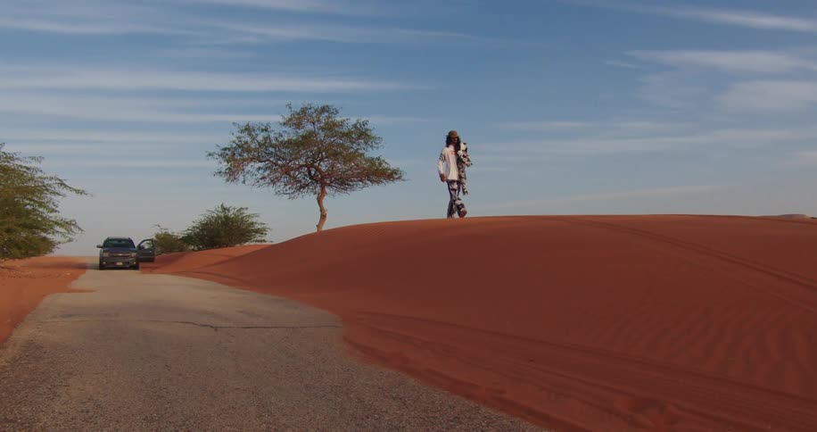 Asphalt street in the middle of a desert with a man walking