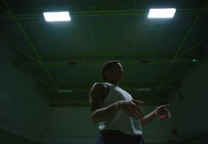 Man wearing a white undershirt and jeans dances in a basketball court