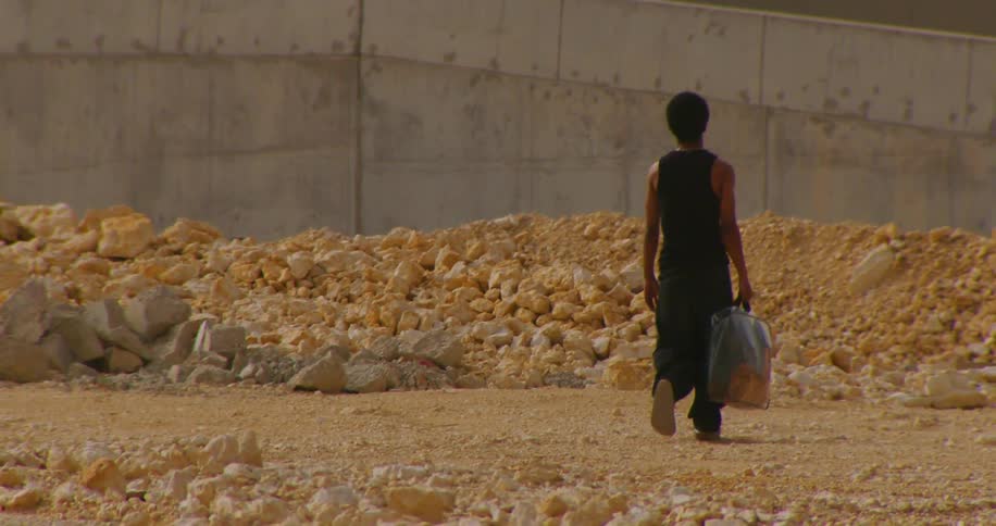 Man holding a bag walking among the stones next to an overpass in the city