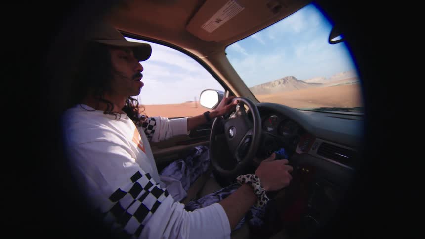 A man drives a car through nature and looks at his smartphone