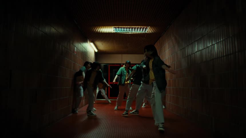 A woman dancing on a dimly lit corridor with duplicates of herself