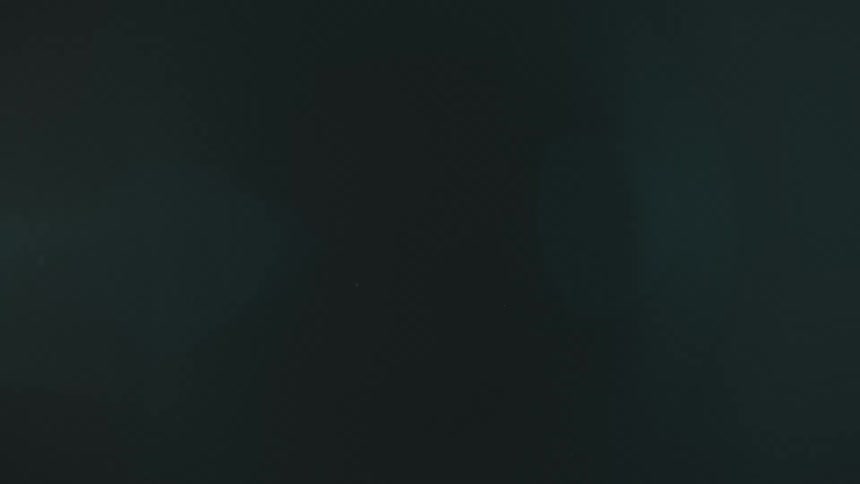 Blurry footage of dimly blue lights moving on a dark background