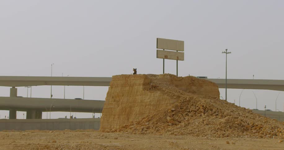 A person on top of a pile of dirt and rocks sorts clothing