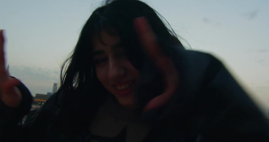 Two teenage girls playing around on a roof while posing for pictures