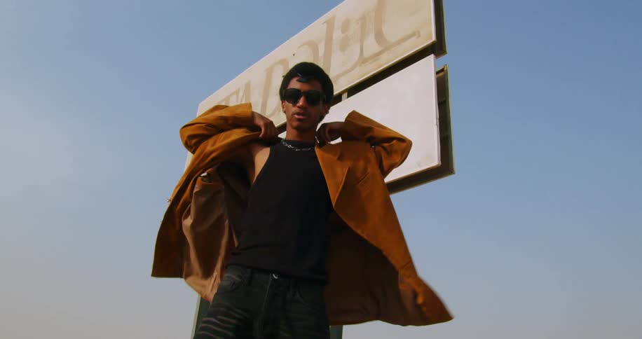 A man tries on a jacket by the billboard sign