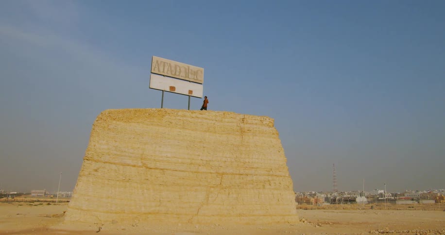 A person stands over a large rectangular block of sandstone near a sign