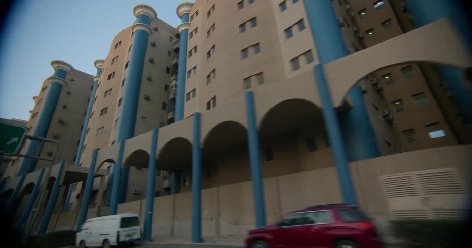 Vehicle passing by apartment buildings with arches and windows in the neighborhood