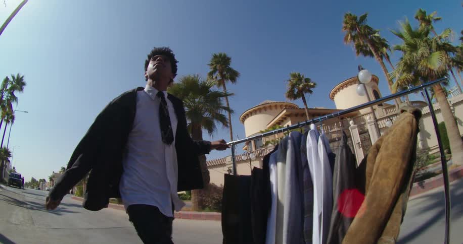 Man walking with a mobile clothesline with hangers and coats down a city street