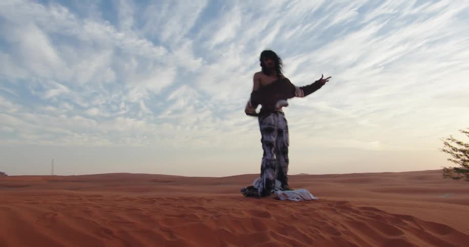 Man wearing a blouse while standing on a dune in a natural location