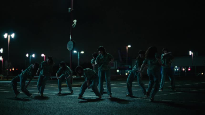 Multiple exposures of a woman dancing in a parking lot at night