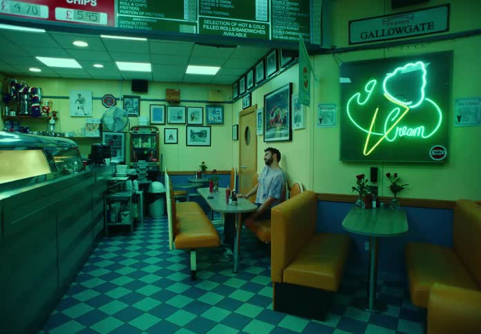 A man is sitting on a bench in a cafe and is moving his head