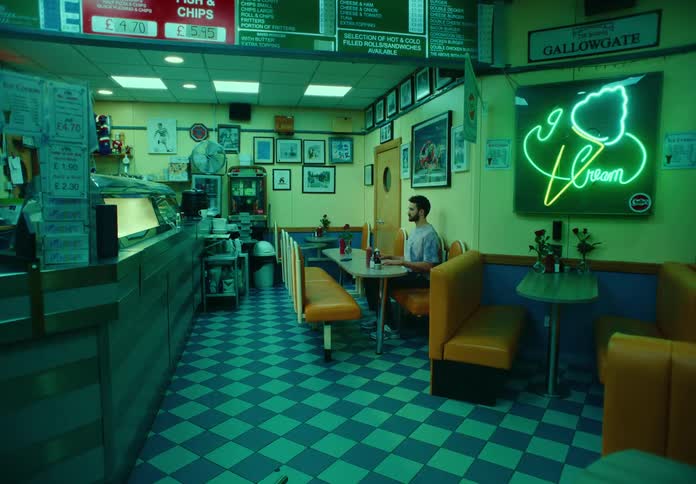 Man sitting in a booth at a retro diner looking around robotically